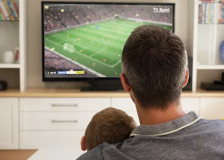 Mann schaut mit Kind Fußball im TV