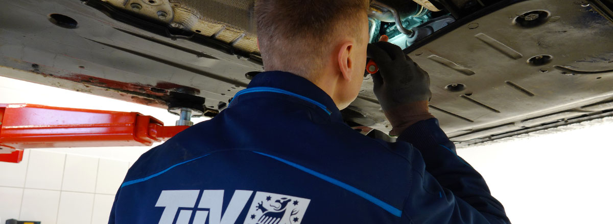 Kfz-Prüfingenieur prüft die Bremsleitung an einem Fahrzeug