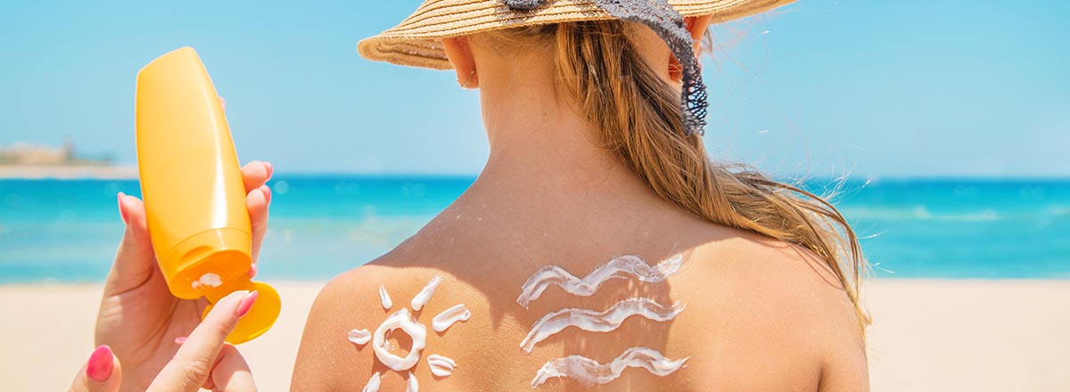 Mutter cremt ihr Kind am Strand mit Sonnencreme ein