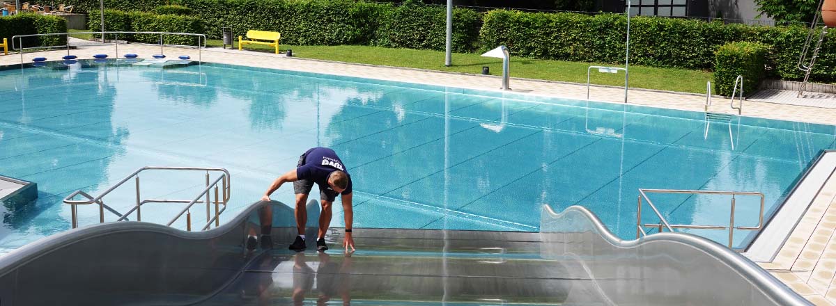 Badesaison ist eröffnet: TÜV Thüringen prüft Wasserrutschen, Sprungtürme und Spielplätze in Freibädern TÜV Sachverständiger beim Prüfen einer Wasser-Wellenrutsche