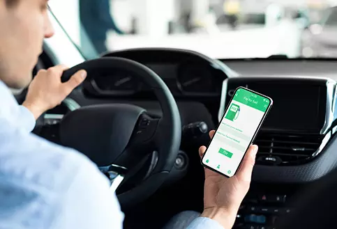Mann schaut im Auto auf seine Tank-App