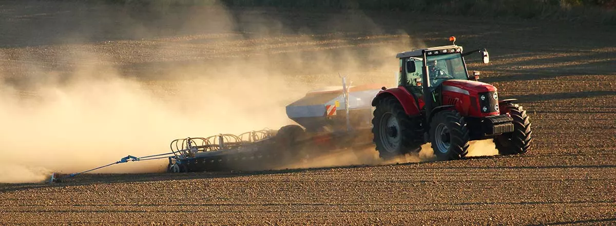 Traktor auf einem Feld mit Staubentwicklung