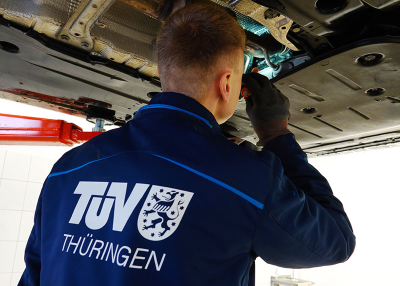 Kfz-Prüfingenieur prüft die Bremsleitung an einem Fahrzeug